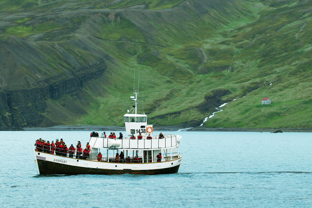 Electric boat sailing towards traditional whale watching areas near Kinnafjöll Mountains in Húsavík, Iceland
