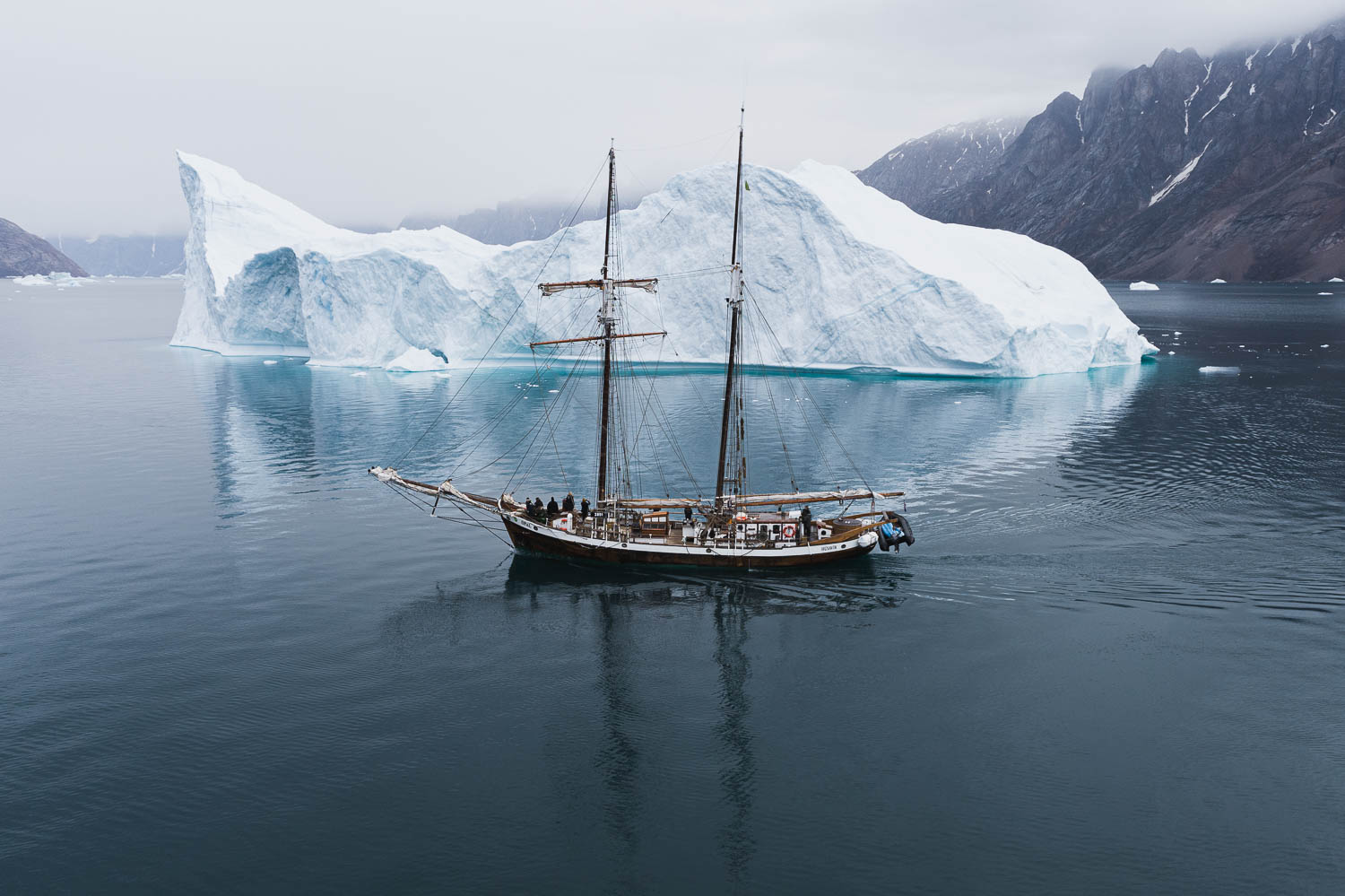 Schooner opal sailing by huge iceberg